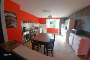 a kitchen with red walls and a table and chairs at Vacances à la campagne 