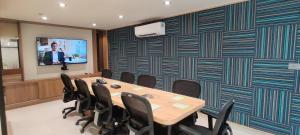 a conference room with a table and chairs and a screen at Indie Stays Jaipur in Jaipur