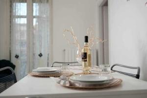 una botella de vino sentada en una mesa con platos en NewLife 815 Holiday Home White, en Mercato San Severino