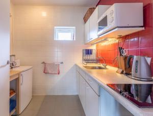 - une petite cuisine avec des placards blancs et du carrelage rouge dans l'établissement Domburgseweg 52 appartement, à Oostkapelle
