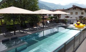 a swimming pool with chairs and umbrellas on a building at Hotel Zum Pinzger in Stumm