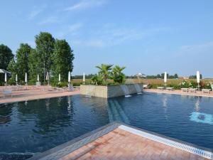 a large pool of water with tables and chairs at Characteristic apartment in Codigoro with pool in Codigoro