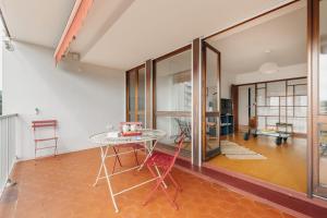 a dining room with a table and glass walls at Sixties 64 2 bedrooms apartment with a balcony and parking in Biarritz in Biarritz