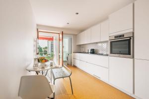 a kitchen with white cabinets and a table at Sixties 64 2 bedrooms apartment with a balcony and parking in Biarritz in Biarritz