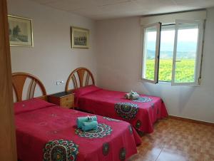 - 2 lits dans une chambre avec des draps rouges et une fenêtre dans l'établissement Hostal Restaurante LA CEPA, à Cenicero