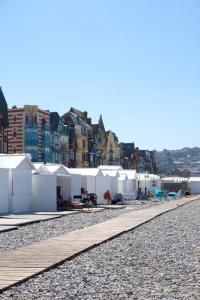 rząd białych namiotów na kamienistej plaży w obiekcie Villa Adèle, Escapade Belle-Époque - Appt 01 w mieście Mers-les-Bains