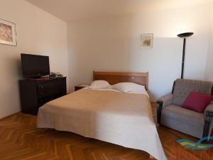 um quarto com uma cama, uma cadeira e uma televisão em Nice apartment with terrace and grill for use em Malinska