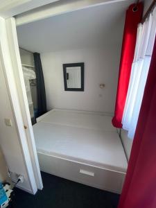 uma pequena cama branca num quarto com uma janela em Appartement 4 personnes em Risoul