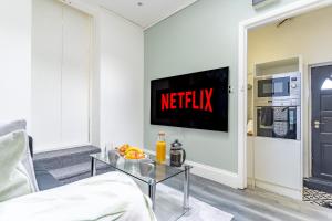 uma sala de estar com televisão e uma mesa com fruta em Prime Location - Cosy Apartment near Emirates Stadium em Londres