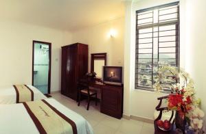 a bedroom with a desk with a television and a window at AMANDA HOTEL ĐÀ NẴNG in Da Nang