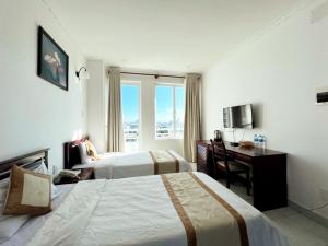 Habitación de hotel con 2 camas y escritorio en AMANDA HOTEL ĐÀ NẴNG en Da Nang