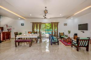 comedor con mesa, sillas y TV en SaffronStays Lakeview Nivara - Farm Stay Villa with Private Pool near Pune en Pune