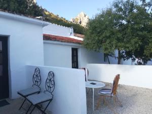 a patio with chairs and a table next to a white wall at Olive Branch El Chorro in El Chorro