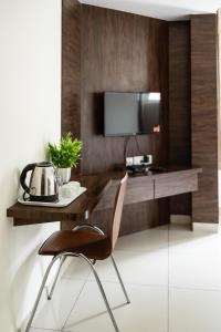 Habitación con escritorio, TV y silla. en Catalyst Suites, Rajaji Nagar, en Bangalore