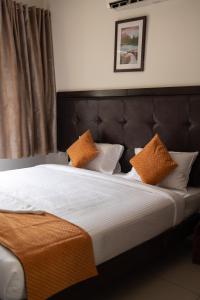 Una cama con almohadas naranjas y blancas. en Catalyst Suites, Rajaji Nagar, en Bangalore