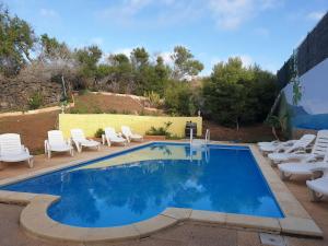 uma piscina com cadeiras brancas e um monte de móveis em Villa Oasis em Chío