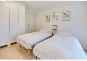 two beds in a room with white walls at Ostende The Waves in Ostend