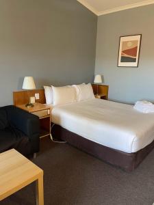 Habitación de hotel con 2 camas y sofá en Waterview Gosford Motor Inn, en Gosford