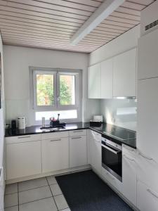 una cocina con armarios blancos y encimeras negras en 2 BR - Kingsize Bett - Garten - Parken - Küche en Zúrich