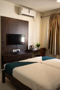 a bedroom with a bed and a flat screen tv at Catalyst Suites, Rajaji Nagar in Bangalore