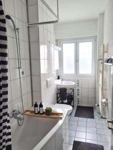 a white bathroom with a tub and a sink at 2 BR - Kingsize Bett - Garten - Parken - Küche in Zürich