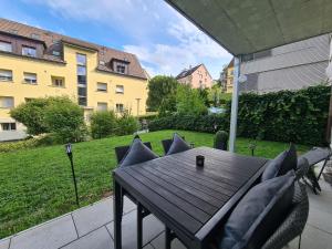 Une table et des chaises en bois sont disponibles sur la terrasse. dans l'établissement 2 BR - Kingsize Bett - Garten - Parken - Küche, à Zurich