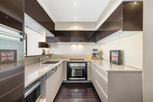 a large kitchen with stainless steel appliances and black cabinets at Penthouse Living Premium Location by Custom Bnb Hosting in Melbourne