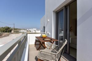 einen Balkon mit einem Holztisch und Stühlen in der Unterkunft Anais Milos Suites in Adamas