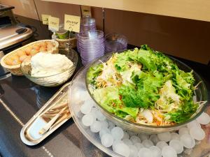 a salad in a bowl on a counter with other foods at Super Hotel Akihabara Suehirocho in Tokyo