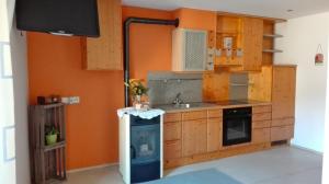 una cucina con pareti arancioni, lavandino e piano cottura di Zum Lindenwirt - Al Tiglio a Naz-Sciaves