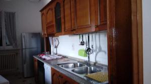 una cocina con fregadero de acero inoxidable y armarios de madera en Casa vacanza IL MELOGRANO Giuggianello (Lecce), en Giuggianello