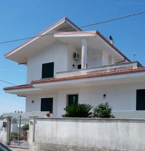 una casa blanca con una valla delante en Casa vacanza IL MELOGRANO Giuggianello (Lecce), en Giuggianello