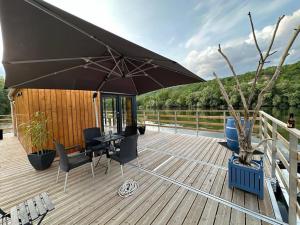 eine Terrasse mit einem Tisch, Stühlen und einem Sonnenschirm in der Unterkunft Rêve sur l’eau in Moisson