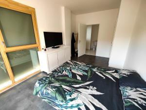 1 dormitorio con 1 cama y TV de pantalla plana en Relaxing Seine Views Apartment from Saint-Denis Island, en LʼÎle-Saint-Denis