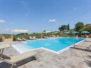a large swimming pool with chairs and umbrellas at Lavish Holiday Home in Volterra with Pool in Volterra
