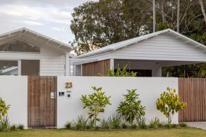 a white fence in front of a house at Brand new coastal oasis - family & pet friendly. in Coolum Beach