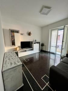 Una sala de estar blanca con un sofá y un televisor. en casetta sopra il mare, en Génova