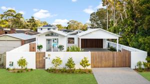 ein weißes Haus mit einem Zaun und Gras in der Unterkunft Brand new coastal oasis - family & pet friendly. in Coolum Beach