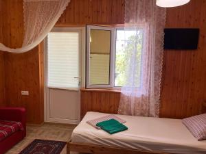 a small bedroom with a bed and a window at Гостевой дом "MARUS" in Tsandrypsh
