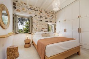 1 dormitorio con 1 cama grande y pared de piedra en Zos Suites en Kanakis