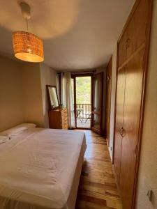 um quarto com uma cama branca e piso em madeira em Your Place Benasque em Benasque