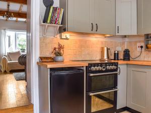 a kitchen with a black stove and white cabinets at Lavender Cottage in Kirkburton