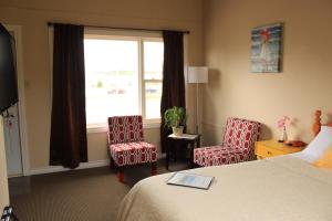 a hotel room with a bed and two chairs and a window at Oasis Motel in Antigonish