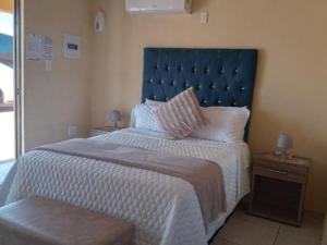 a bedroom with a large bed with a blue headboard at Maboe Leisure Resort in Rustenburg