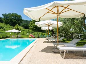 BiscinaにあるFarmhouse in hilly area in Gubbio with poolのプール(パラソルとラウンジチェア付)