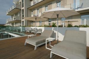 eine Terrasse mit Stühlen und einem Sonnenschirm auf dem Balkon in der Unterkunft Hotel Palazzo del Garda & Spa in Desenzano del Garda
