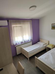 2 camas en una habitación con paredes de color púrpura y ventana en Hotel MK, Plavi restoran, Loznica, en Loznica