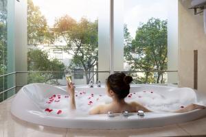 a woman sitting in a bath tub with a glass of champagne at Harmony Saigon Hotel & Spa in Ho Chi Minh City +88 photos