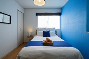 ein blaues Schlafzimmer mit einem Bett mit zwei Handtüchern darauf in der Unterkunft 海まで徒歩1分 浜比嘉島まで車で10分 12名宿泊可能な宿泊施設 エムズハウス in Uruma