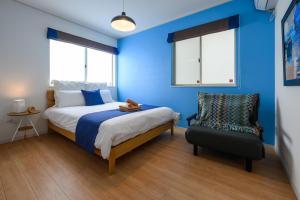 うるま市にある海まで徒歩1分 浜比嘉島まで車で10分 12名宿泊可能な宿泊施設 エムズハウスの青い壁のベッドルーム1室、ベッド1台、椅子1脚が備わります。